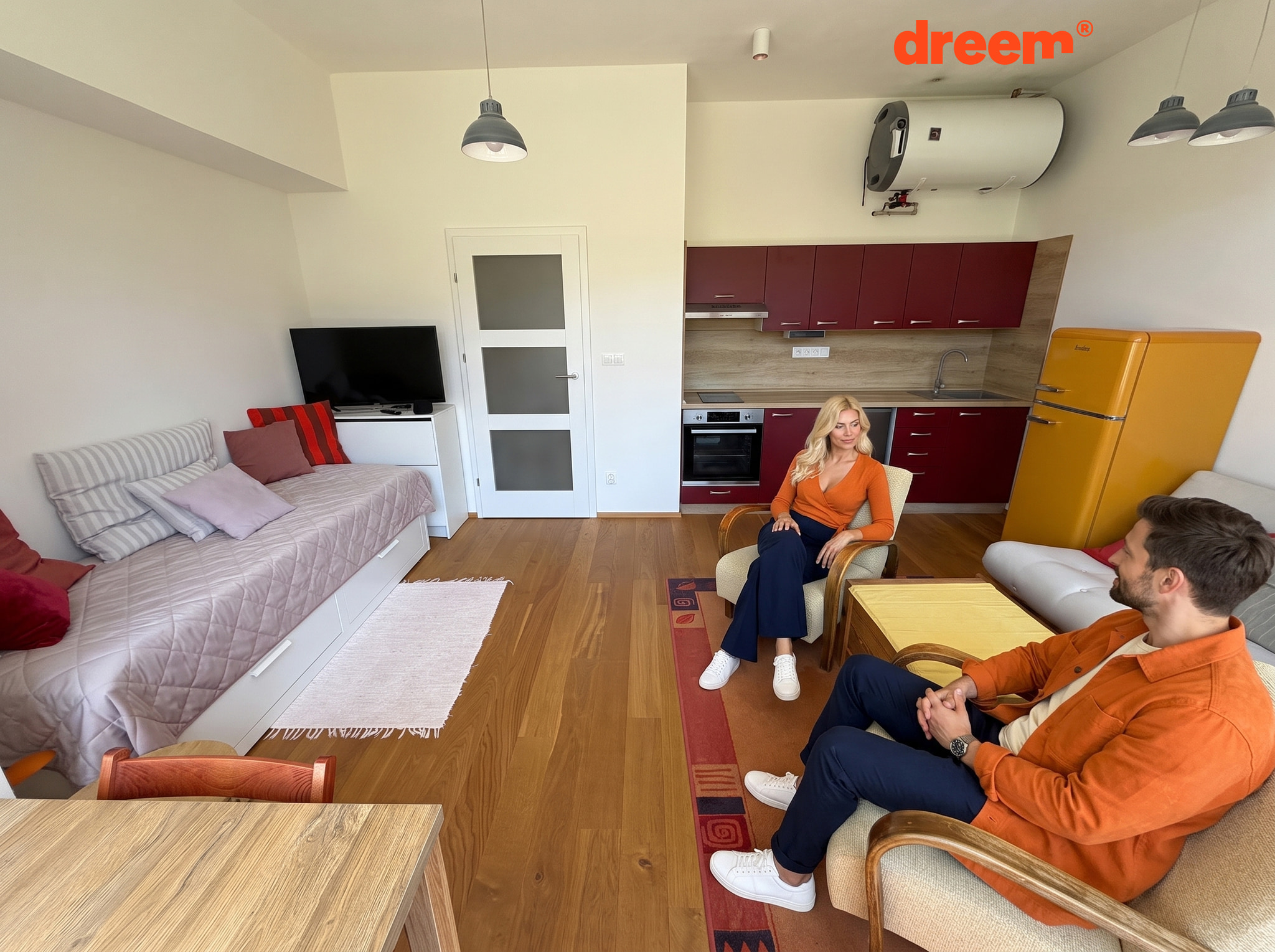 Světlý obývací pokoj propojený s tmavě červenou kuchyňskou linkou, žlutou lednicí, pohovkami a křesly na dřevěné podlaze
