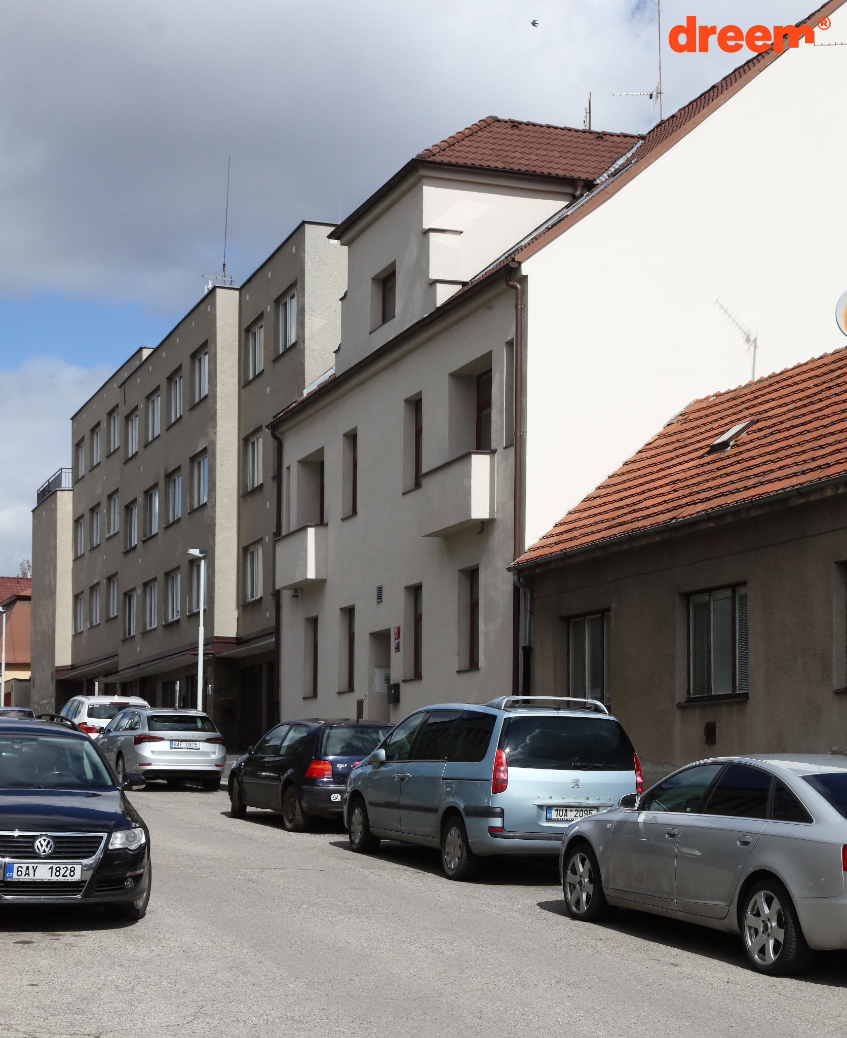 Vícepodlažní bytové domy v městské zástavbě s parkujícími auty podél ulice