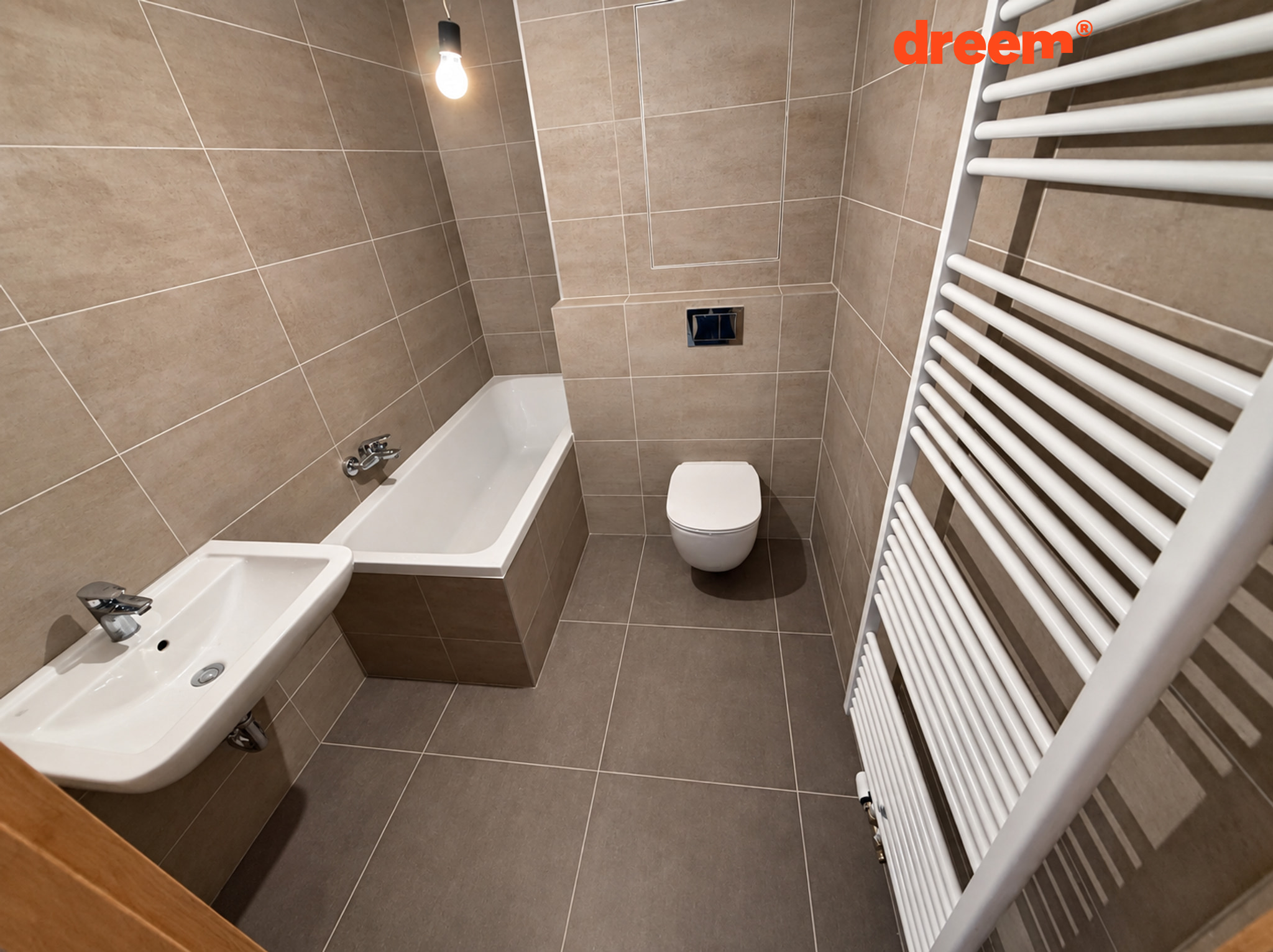 Moderní koupelna s hnědým obkladem, vanou, závěsným WC, umyvadlem a bílým topným žebříkem